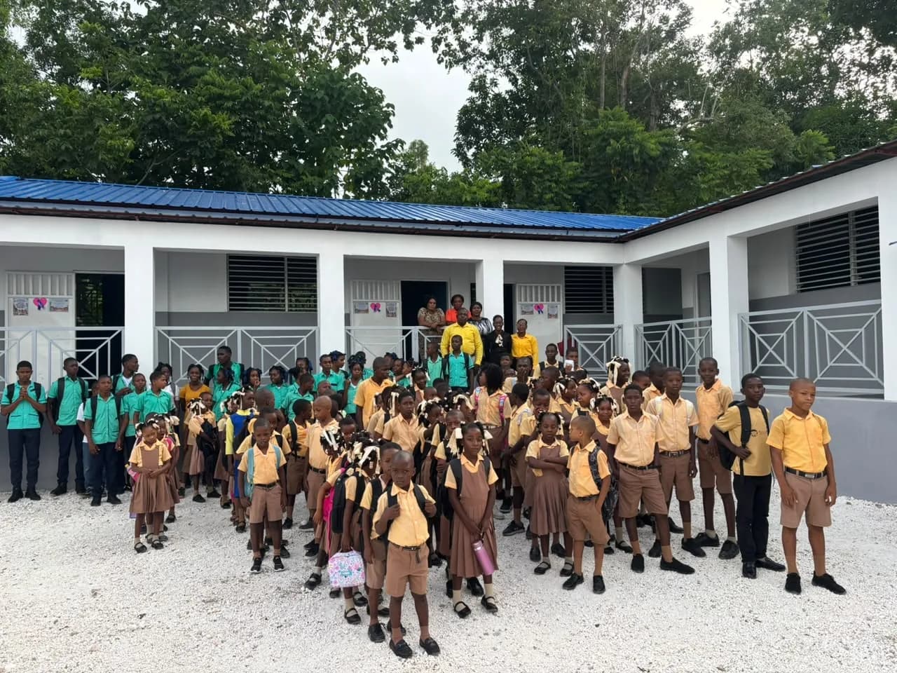 Students gather in front of a newly built HEF school with a blue roof