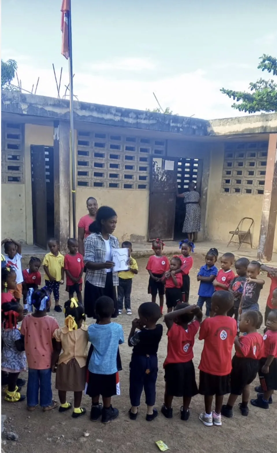 Children gather in the yard of an HEF school beneath the Haitian flag