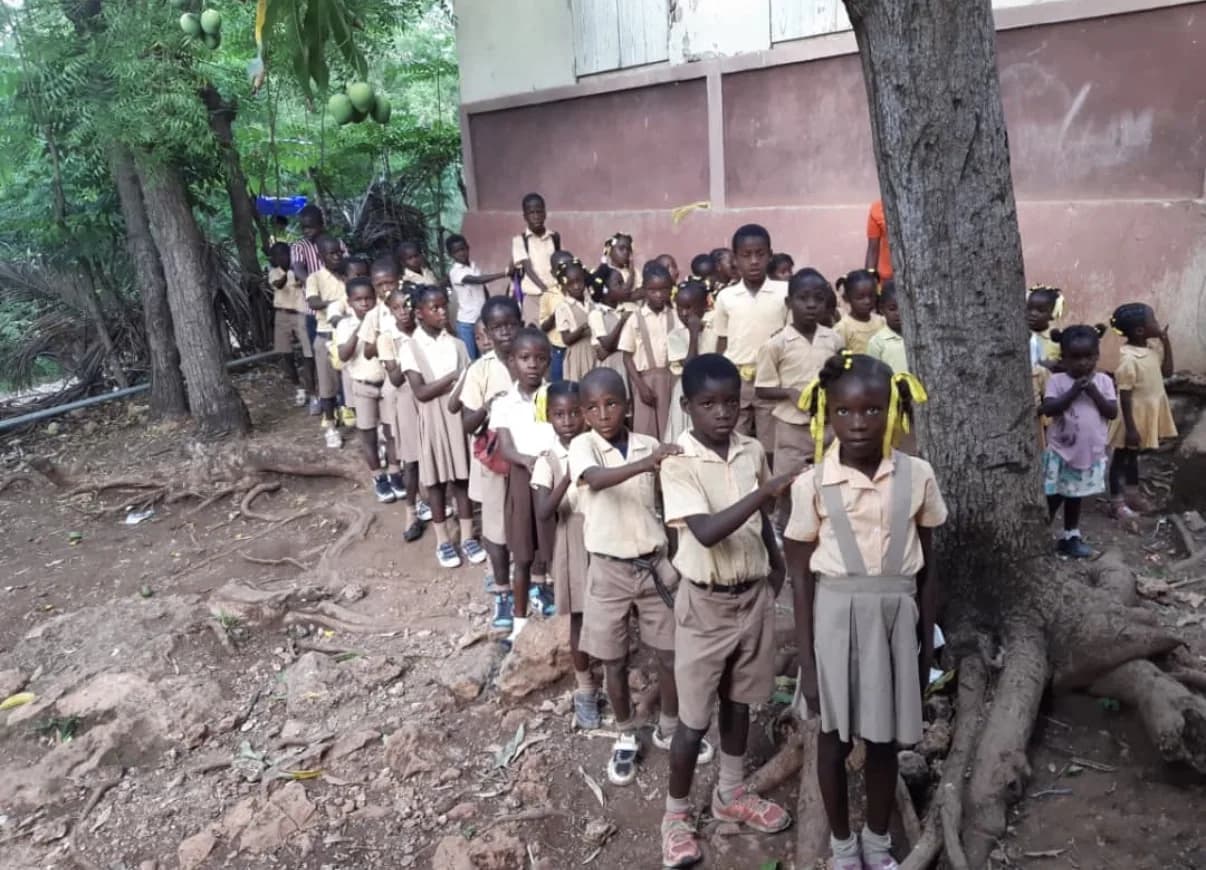 A class in tan uniforms lines up outside its school in the mountains of southern Haiti