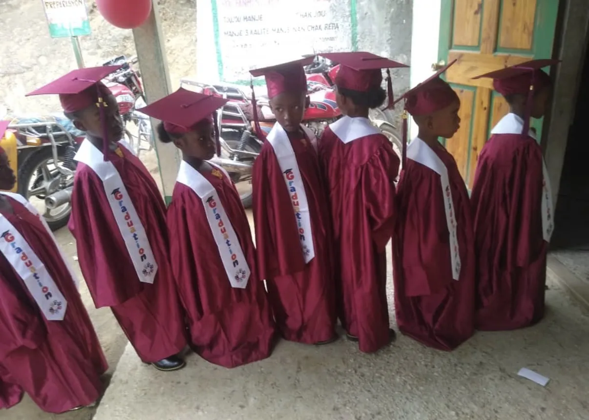 Graduates in maroon caps and gowns line up at an HEF school