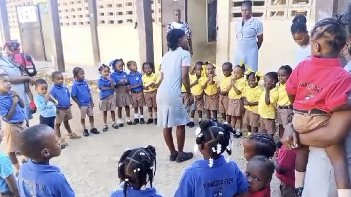 Kindergarten children gather in a circle with their teachers in a school courtyard
