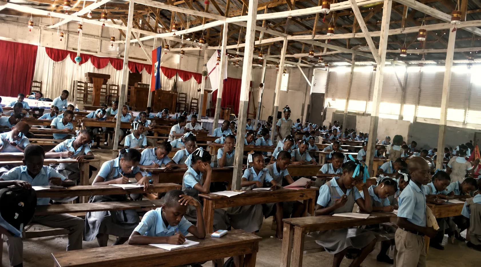 A large classroom full of students working at wooden desks