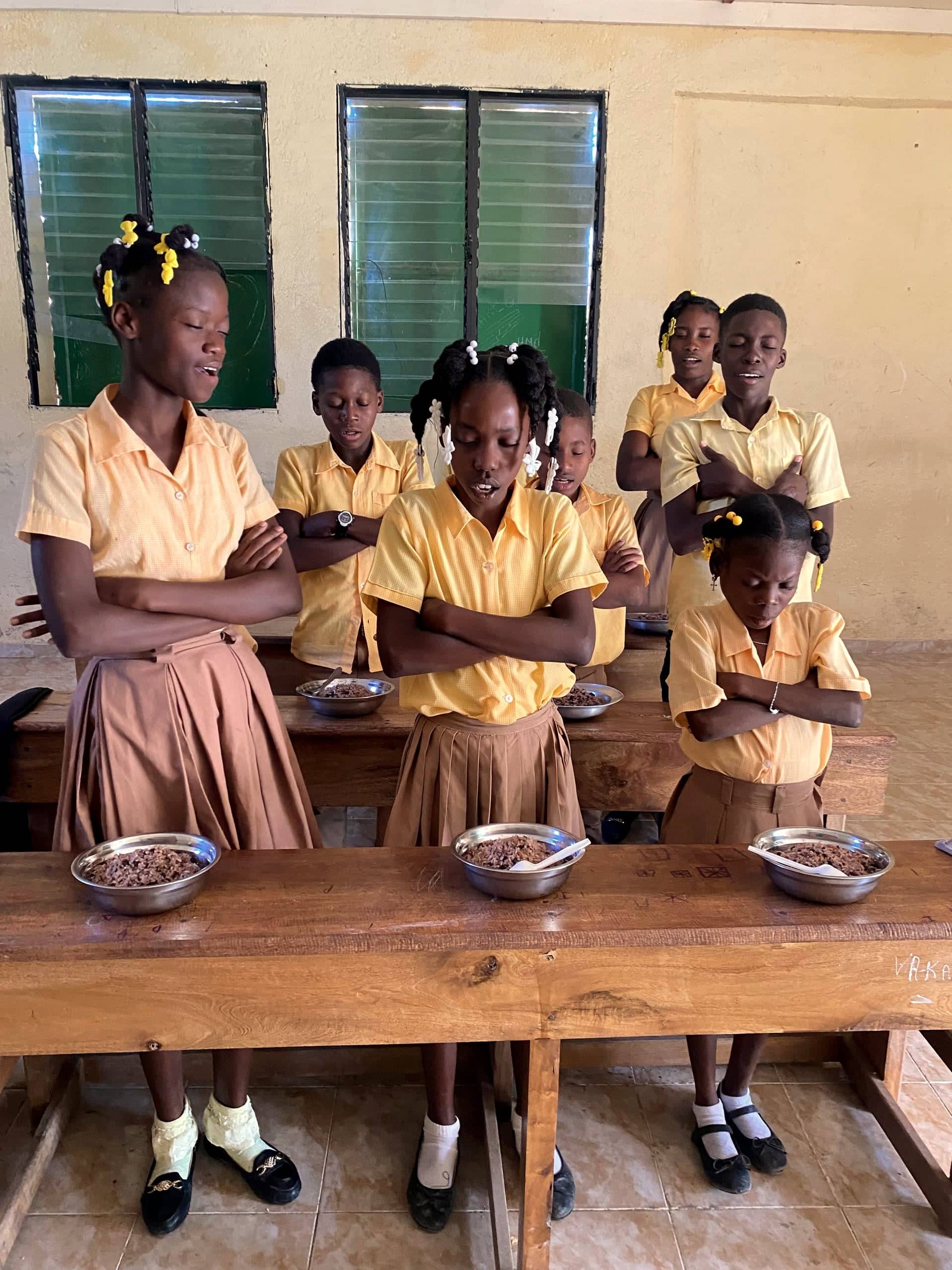 Students standing together in prayer before a meal at an HEF school in the mountains of southern Haiti