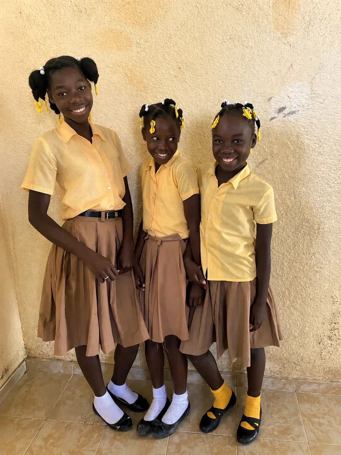 Three young girls in school uniforms pose together for a portrait
