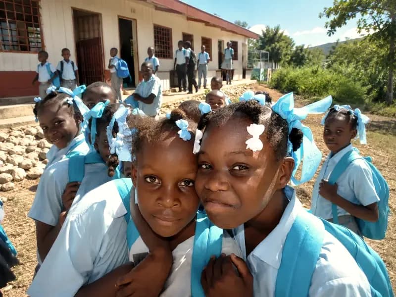 Two students in blue uniforms smiling at an HEF school